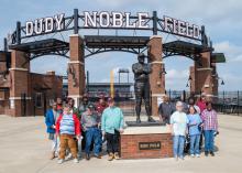 A group of people stands outside around a statue.