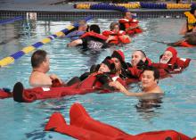 Mississippi State University Extension Service instructor Peter Nguyen, right foreground, helps commercial fishermen practice getting into survival suits at a Gulf Coast swimming pool. (Photo by MS-AL Sea Grant Consortium/Melissa Schneider)