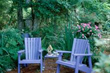 The mirror hanging on the tree over the left Adirondack chair blends comfortably into this lovely home-like setting.