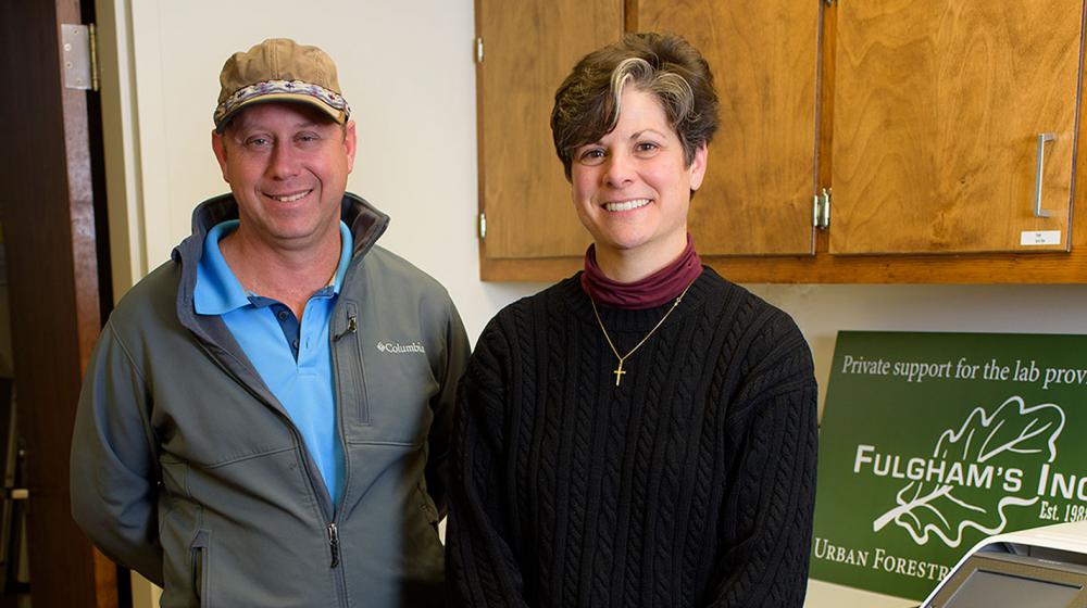 David Fulgham and Clarissa Balbalian A man wearing a light blue collared shirt and a grey zip-up jacket stands next to a short-haired woman wearing a black sweater.