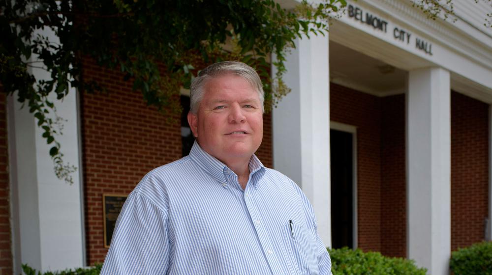 Buddy Wiltshire, Mayor of Belmont A man wearing a light blue and white striped shirt and blue jeans stands in front of Belmont City Hall.