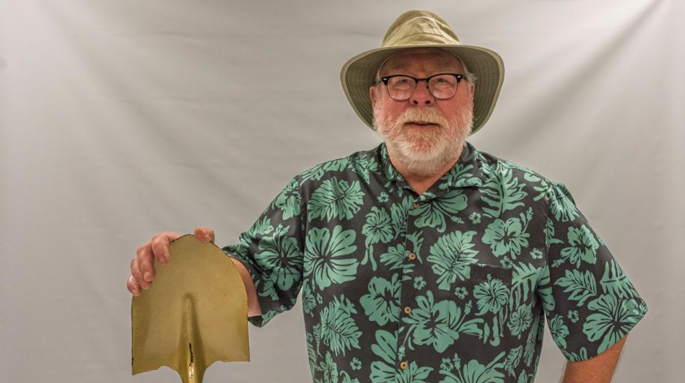 A smiling man wearing a cowboy hat and Hawaiian shirt.