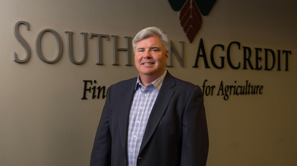 A man standing inside in front of the Southern AgCredit wordmark on a wall.
