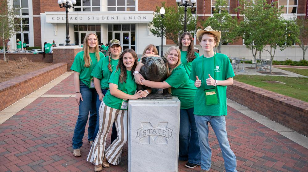 Students in green shirts posing for a picture.