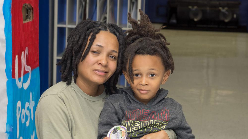 A mother embraces her son in a school hallway.