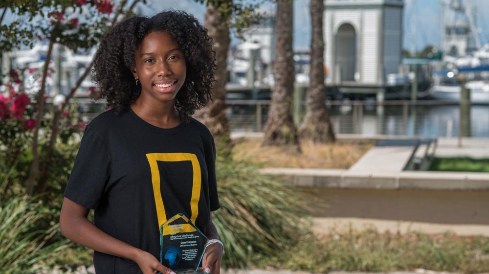 A young woman smiling and holding a trophy.