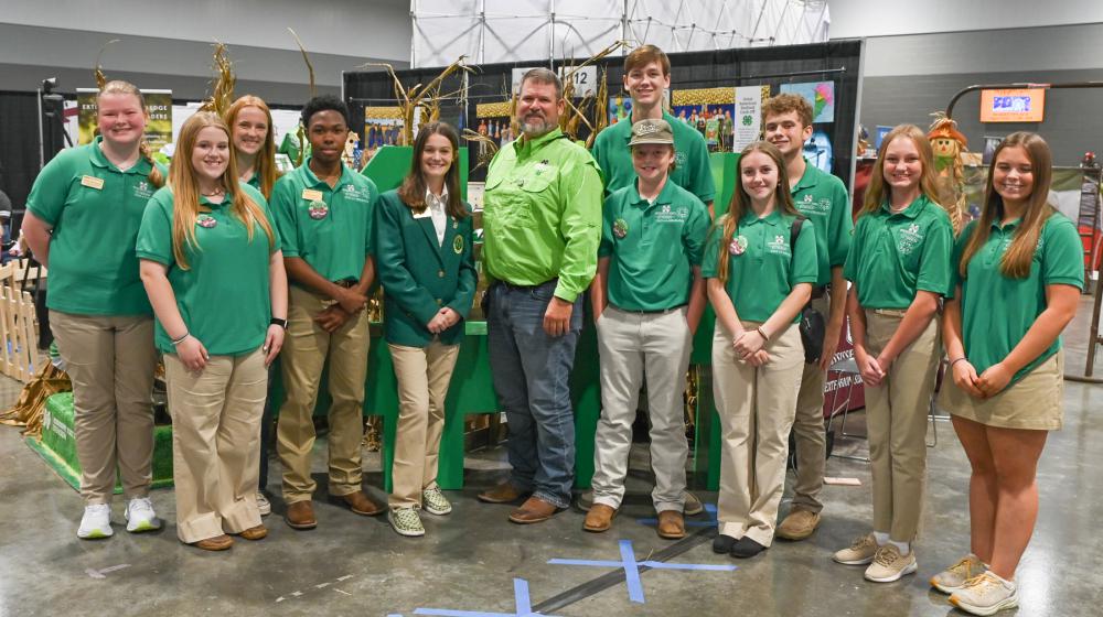A large group of people, standing, smiling, and wearing green shirts.
