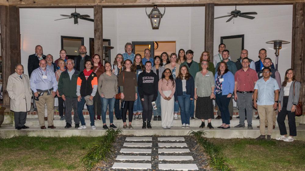 A large group of people standing on a covered patio.