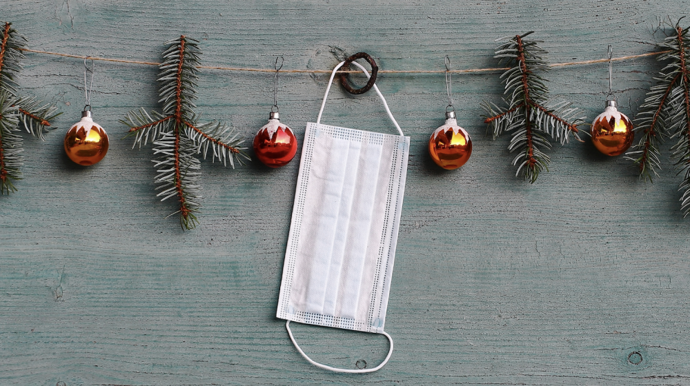 A white mask hanging on Christmas garland.