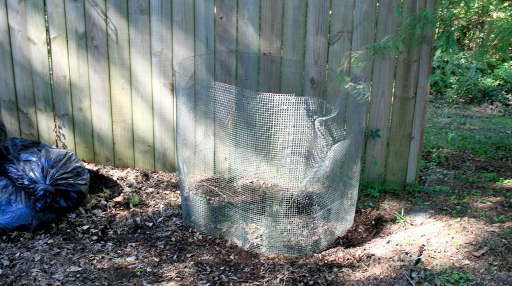 A piece of hardware cloth encircles a small, layered pile of organic waste.