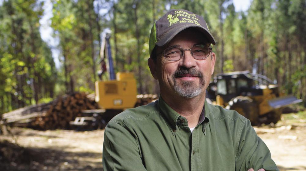 A man stands near a logging operation.