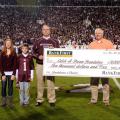 BankFirst made a donation to the Catch-A-Dream Foundation every time the Mississippi State University Bulldogs scored touchdowns. BankFirst's Jerry Wilson, left, presents a ceremonial check for $10,000 to Marty Brunson at the MSU-Arkansas game Nov. 20. Wilson is accompanied by his grandchildren, Mauri and Miller Wilson. (Photo by MSU Ag Communications/Kat Lawrence)