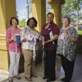 4 women holding mastectomy drain pouch bags—small, square sacks laced with ribbon