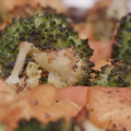 Roasted and seasoned broccoli florets, sweet potato chunks, and whole baby carrots on a foil covered sheet pan. 