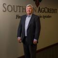 A man standing inside in front of the Southern AgCredit wordmark on a wall.