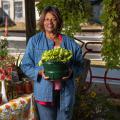 A woman smiling and holding a planter full of lettuce.