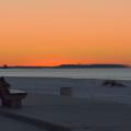 An orange sunset on Biloxi beach with the Gulf of Mexico in the background.