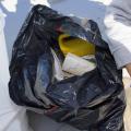 Plastic debris is seen in an open black trash bag sitting on the beach at the 2016 Mississippi Coastal Cleanup.