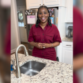 A woman stands at the kitchen sink.