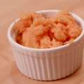 Mashed sweet potatoes in a white ceramic ramekin on a butcher block table.