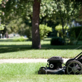 A black lawn mower mowing a yard.