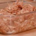 Shredded chicken breasts coated in barbecue sauce in a rectangular, clear-glass container.