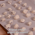 Red grapes dipped in a mixture of peanut butter and Greek yogurt lined up on a parchment paper covered baking sheet. 