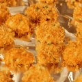 Chicken nuggets coated in golden brown panko breadcrumbs on an aluminum-foil lined baking sheet. 