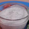 Homemade ranch dressing in a clear glass bowl atop a turquoise blue plate, surrounded by baby carrots, broccoli florets, and grape tomatoes.