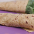  Green lettuce and cooked chicken wrapped in a wheat tortilla. 