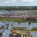 Metal roofs of poultry houses lie on the ground in rows amid twisted metal and debris.