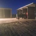 A tractor parked outside of a shed at night.