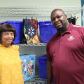 A woman and a man pose in front of shopping bags and blue crates.