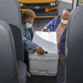 Two women load an ice chest on a bus.