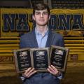 A young man holds three plaques.	