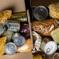 A box of food to donate, including beans, pasta, and canned goods.