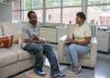 A man and woman sit opposite one another while talking.