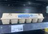 A carton of eggs on a grocery store shelf with an affixed price tag.