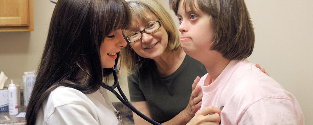 A Rural Medical Scholar has stethoscope to childs' chest while a woman observes.