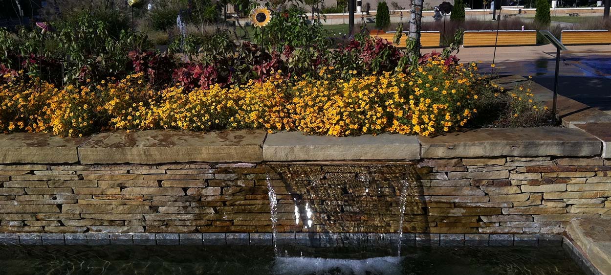 A landscape using colorful flowers and a waterfall.